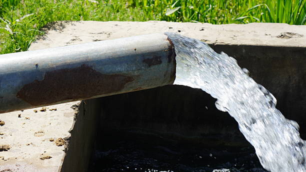 istock Water Flowing from Metal Pipe into Irrigation Ditch 2239007067