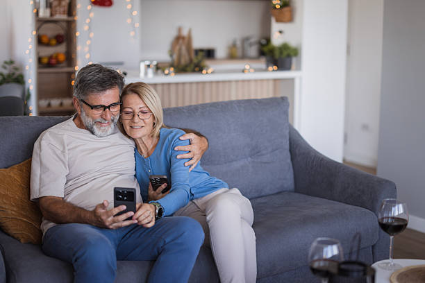 istock Mature couple relaxing on sofa looking at smart phone 2239033270