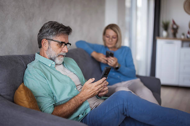 istock Senior couple using smartphones on the couch disconnected 2239033415