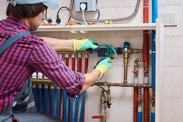 Engineer plumber inspecting and adjusting central heating boiler and water pipes, performing maintenance and diagnostics in home