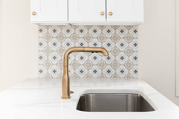 istock A gold kitchen faucet in a white kitchen with a tiled backsplash. 2239036571