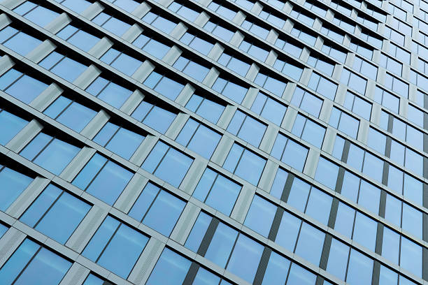 A sleek high-rise facade featuring a uniform grid of blue-tinted windows and metal frames creates a calm, orderly, and contemporary urban aesthetic suitable for business and architecture themes.