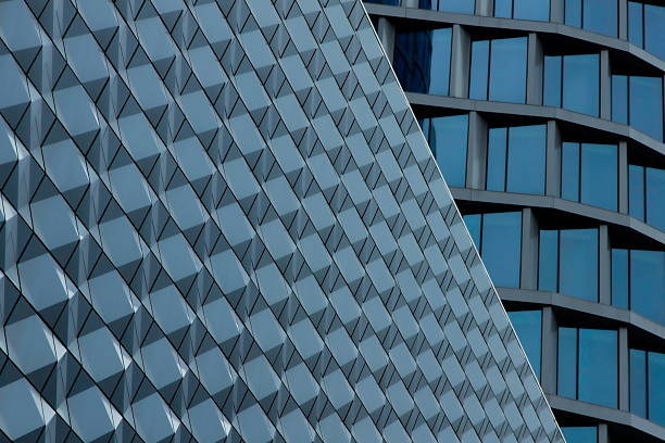 A striking close-up of contemporary architecture featuring a diagonal, tessellated facade and blue-tinted glass. The repetitive geometric shapes convey precision, modernity, and a sense of orderly urban design.