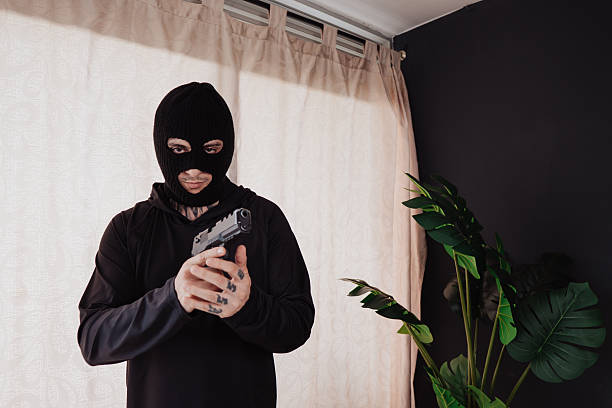 istock A hooded robber with a gun breaks into a house. 2239039395
