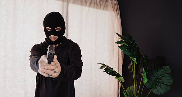 istock A hooded robber with a gun breaks into a house. 2239039396