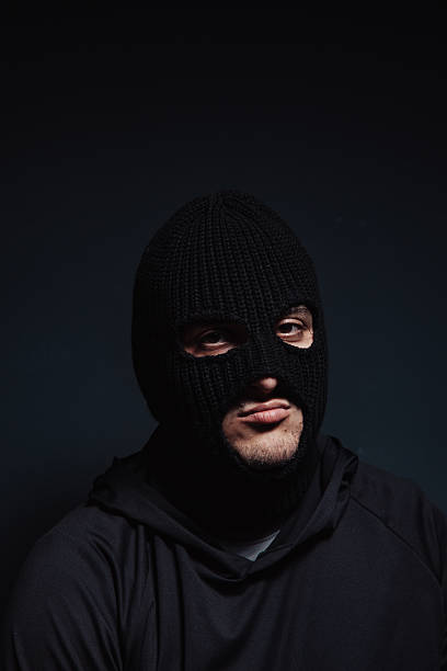 istock masked robber looking at the camera on a black background 2239039536
