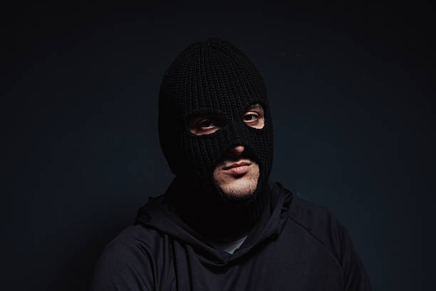 istock masked robber looking at the camera on a black background 2239039550
