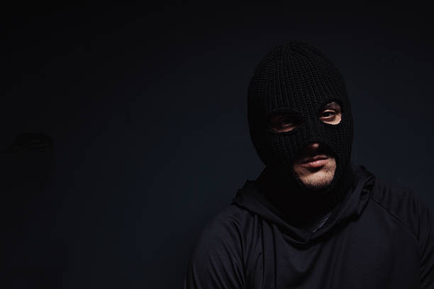 istock masked robber looking at the camera on a black background 2239039576