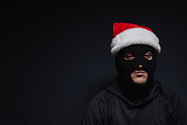 istock masked robber with Christmas hat on a black background 2239039581