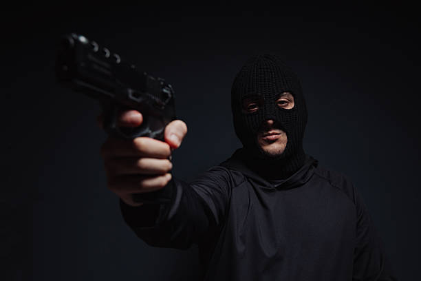istock masked robber with Christmas hat holding a gun on black background 2239039710