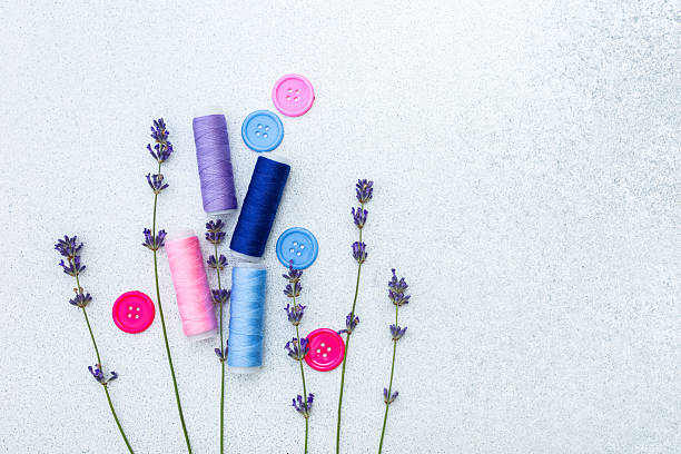 Colorful threads and buttons arranged with lavender on a soft surface
