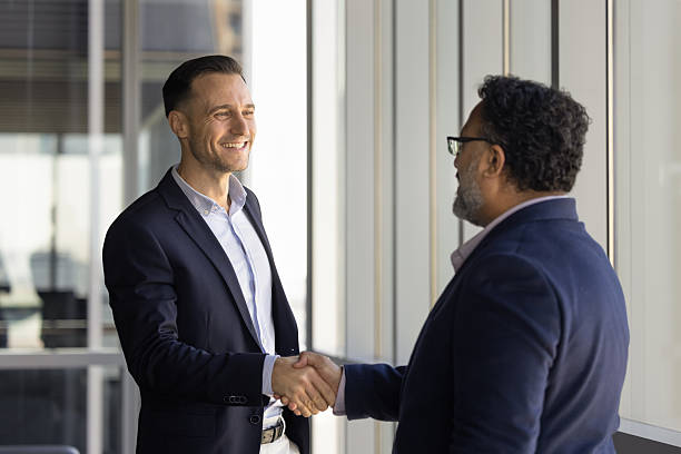 istock Happy diverse businessman and mature customer shaking hands in office 2239047848