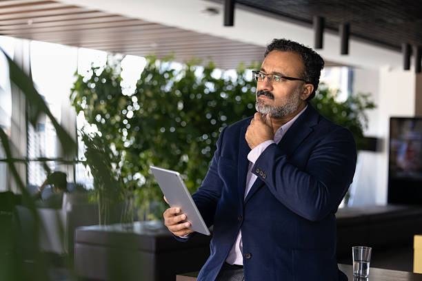 istock Serious successful senior businessman using gadget in company office hall 2239050675