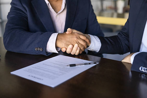 istock Two younger and elder businessmen shaking hands at paper contract 2239053375
