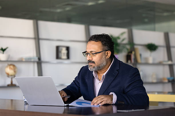 istock Serious busy elder Indian executive using online business application 2239054510