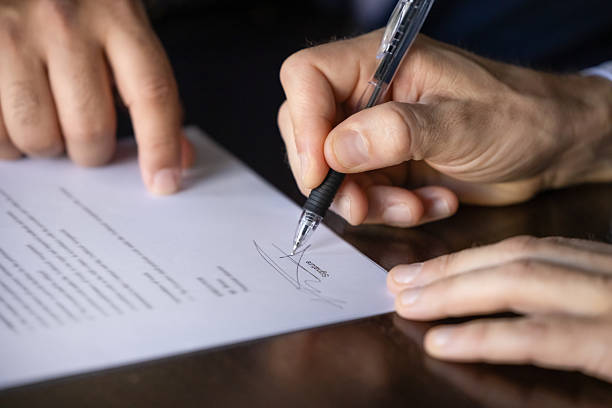 istock Hands of legal advisor pointing at document for client signing 2239058058