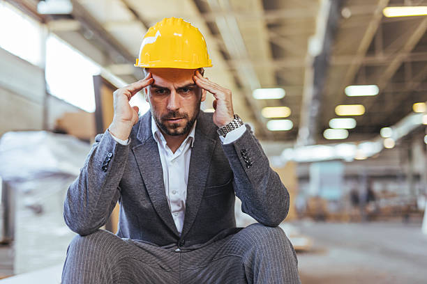 istock Pensive Businessman Wearing a Hard Hat in an Industrial Setting 2239068172