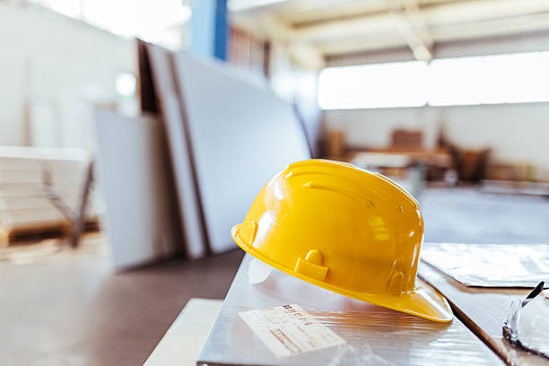 istock Yellow Safety Helmet on a Construction Workspace Table Indoors 2239068236