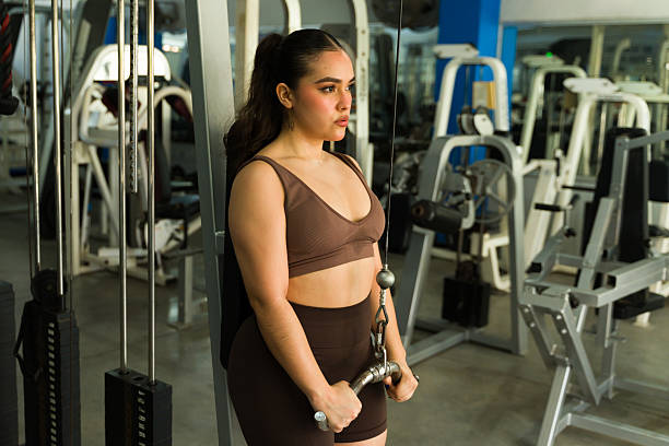 Latin woman working out using a cable machine. Building strength and enjoying fitness training at the health club