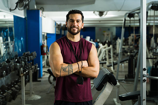 Male personal trainer standing in a gym, confident and experienced, ready to help with fitness and workout