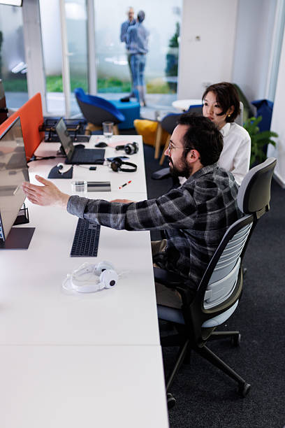 istock Business professionals collaborate on a project in a modern workspace with technology and creative furniture in the background 2239070403