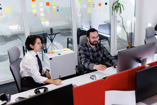 istock Business professionals discussing project details in a modern office space during the day while collaborating on a computer 2239070417