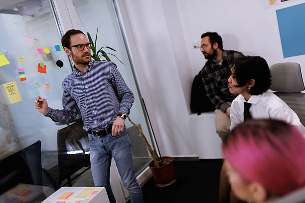 istock Business discussion in modern office with colleagues engaging in brainstorming session using sticky notes 2239070445