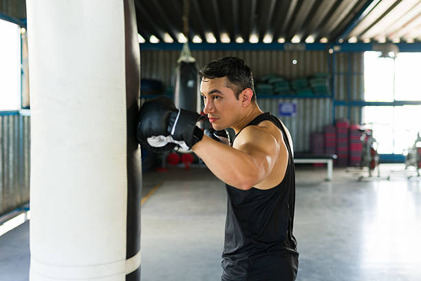 istock Latin man boxing punching bag in gym workout 2239071475