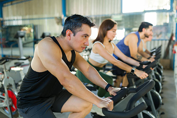 Mid adult man cycling on the exercise bike at the gym