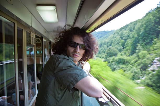 Young man traveling by train looking at camera