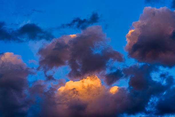 Sky replacement background image of vibrant warm clouds lit at sunset with crisp blue sky.
