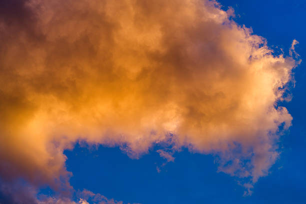 Sky replacement background image of vibrant warm clouds lit at sunset with crisp blue sky.