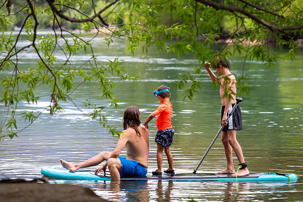 istock Brothers and cousin paddle-boarding on the river 2239081231