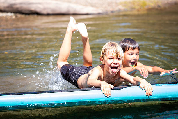 istock Two funny children playing on a paddle board on the riverbank 2239081340