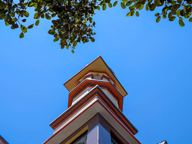 a tall mosque tower topped with a colorful mosaic dome, taken under a blue sky with white clouds