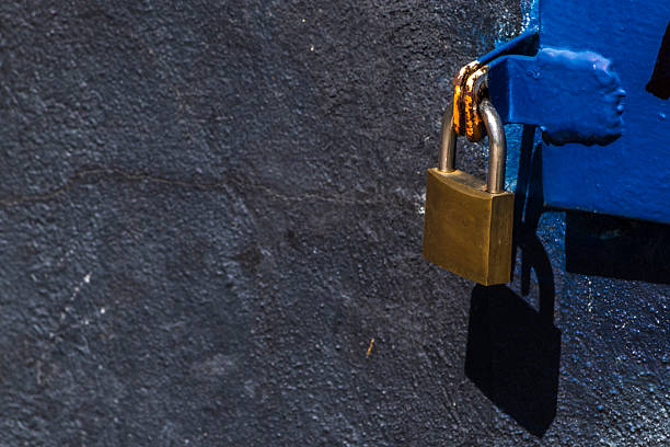 Close-up of three old rusty padlocks attached to a hook set in the concrete