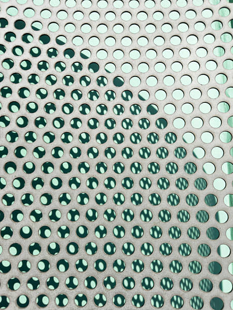 istock Perforated metal mesh with circles and geometric shadows projected onto a green wall 2239096982