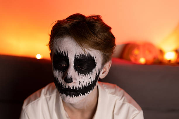 istock boy with skeleton face paint,grinning widely at a Halloween party,surrounded 2239107697