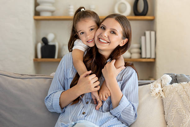 istock Smiling daughter leaning next to mother while spending time together on sofa 2239108162