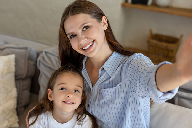istock Mother taking pov selfie with daughter while sitting together on sofa 2239108164