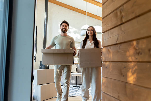 istock Two people with cardboard boxes entering a house and looking contented 2239108239
