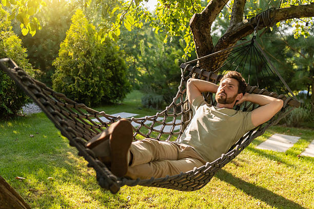 istock Bearded young man lying in a hammock and feeling relaxed 2239108264