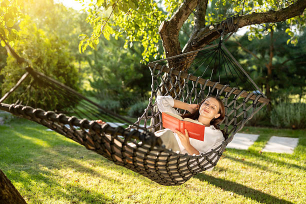 istock Long-haired caucasian young woman enjoying leisure while lying in hammock with a book 2239108290