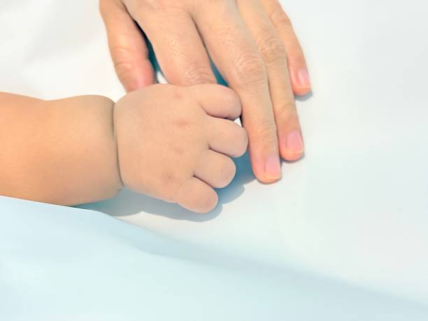 istock Parent and Baby Holding Hands on Soft White Background 2239111256
