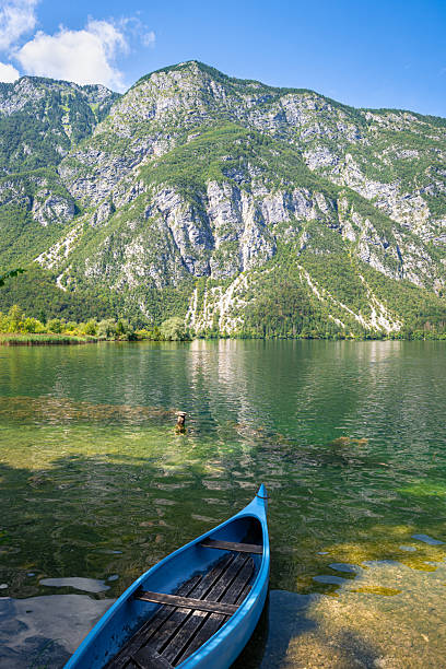 istock Tranquil mountain lake with blue canoe, reflections and towering cliffs. 2239116878