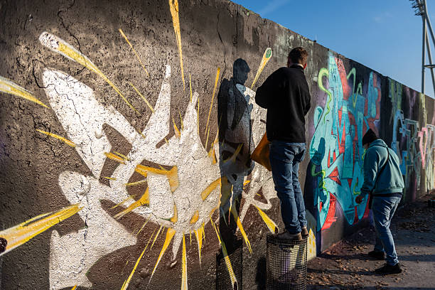 Berlin, Germany - November 13, 2022. Impression of street artists repainting remnants of the historic Berlin Wall at the Mauerpark.