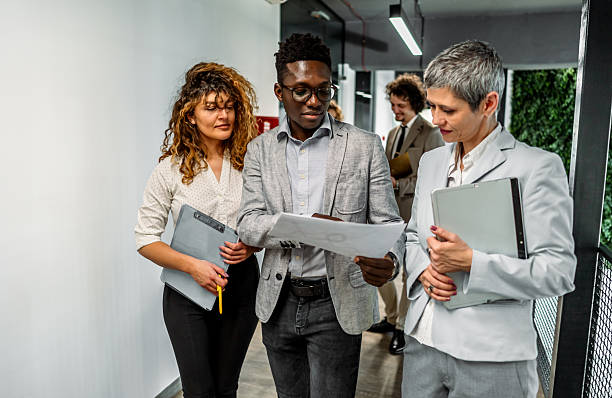istock Business colleagues walking and discussing documents in office hallway 2239127280