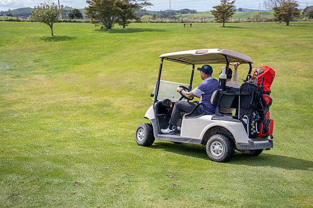 The player keeps the score on the golf course. The score placed on the steering wheel of the golf car. In the background the fairway