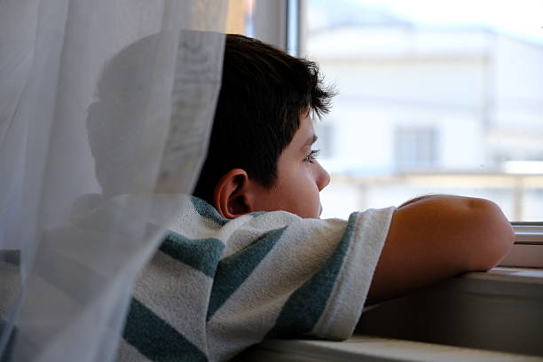 The little boy looks out the window anxiously