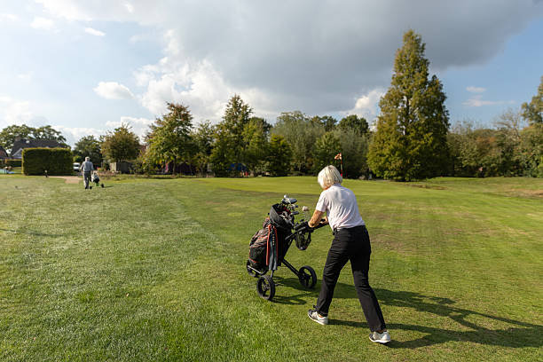 Senior retired couple made up of a beautiful woman and handsome man playing golf together on a course in the Netherlands, Europe